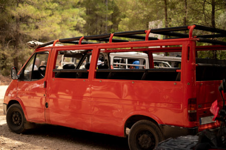 A red open-top tourist bus stands in the forest. Used for tourist agencies, bus tours, excursions,...