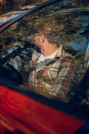 Man driving a car, utilizing modern technology in the vehicle, promoting safe driving practices.の写真素材