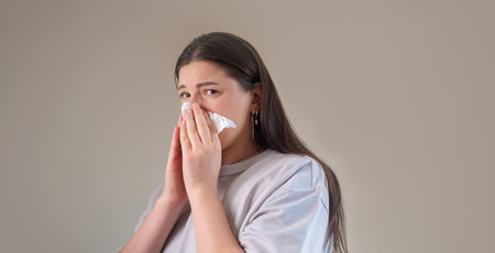 Using a tissue to clean the nose, with nasal moisturizing and cleansing products nearby for sinus care.の写真素材