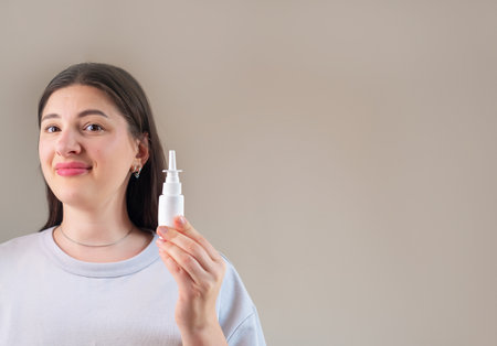 Woman holds a nasal spray for allergies, suitable for sensitive and irritated nasal passages.の写真素材
