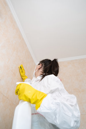 Protective respiratory and skin gear for handling toxic substances, woman in a suit and mask removing mold safely.の写真素材