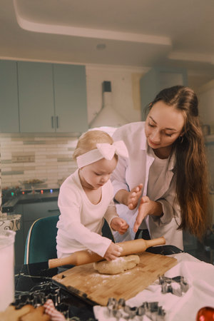 Mom and daughter baking gingerbread cookies together, creating a festive atmosphere of warmth and...