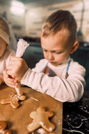 Happy children joyfully decorate cookies with icing, embracing the Christmas tradition of baking...