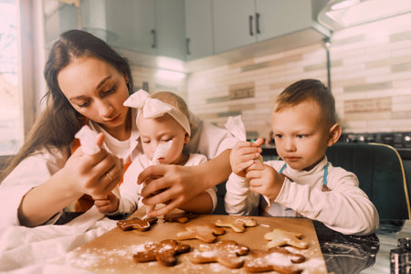 Top view of a mother and children decorating gingerbread cookies with icing, enjoying quality family time on winter evenings.の写真素材