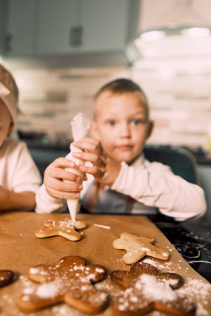 Happy children joyfully decorate cookies with icing, embracing the Christmas tradition of baking gingerbread together.の写真素材