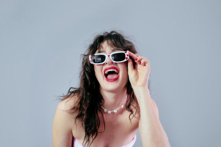 Woman holding her glasses frame and smiling widely, ready for a party celebration.の写真素材