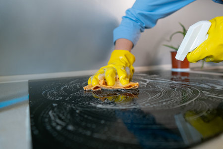 Woman doing housework cleaning kitchen tiles with cleaning products while wearing protective gloves.の写真素材