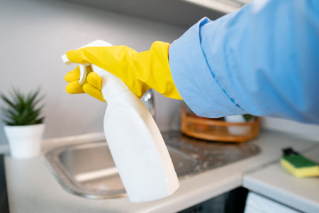 Gloved hands holding cleaning products, woman carefully cleaning and organizing her home with love and attention to detail.の写真素材