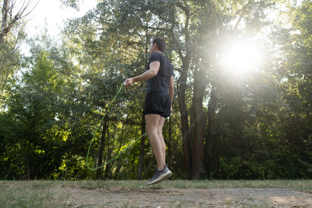 A simple yet effective way to stay healthy: a man exercises with a jump rope outdoors in a green park.の写真素材