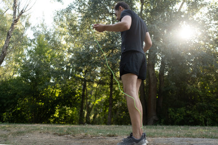 An inspiring workout: a man jumps rope in the park, boosting his endurance and physical condition.の写真素材