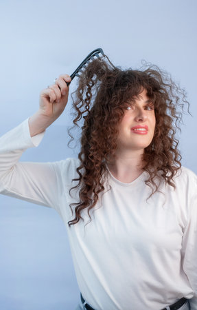Young woman feels discomfort from tangled curly hair and hair loss showing frustration and concern.