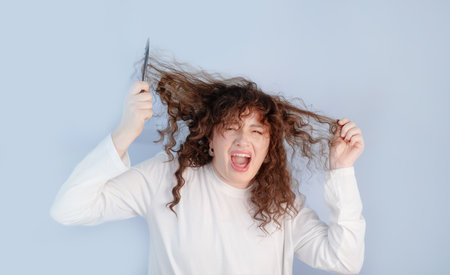 Young woman feels strong discomfort and stress struggling with curly hair care and managing...