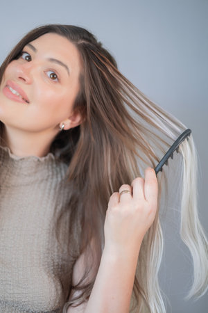 Special comb for hair extensions young woman gently caring for strands in professional beauty salonの写真素材