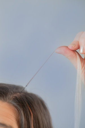 Woman holding hair strand with capsule before applying professional hair extension technique in beauty salonの写真素材