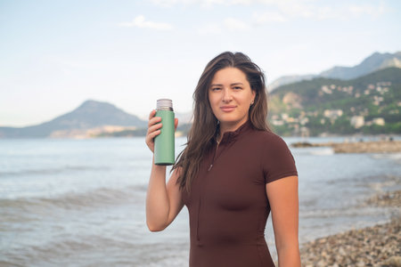 Healthy morning by the ocean. Sporty woman hydrating and relaxing after exercise.の写真素材
