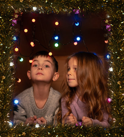Boy and girl in festive sweaters laughing in decorated Christmas setting feeling joy and holiday...