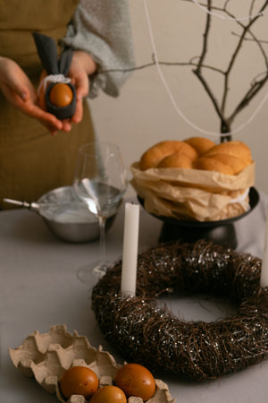 Woman preparing the Easter table, lovingly arranging eggs and candles, creating a festive family...