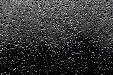 Background photo of rain drops on dark glass, different sizeの写真素材
