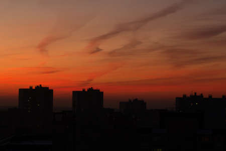 Colorful orange-red sky and clouds during sunrise and sunset with an urban silhouetteの写真素材