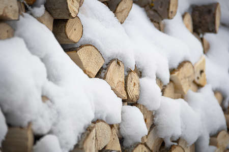 Chopped stock of firewood under the snow. The concept of warmth and comfort in winter. Stove, hearth.の写真素材
