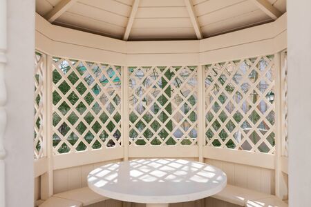 Beautiful white wooden garden house arbour for relaxing in the park sunny summer day