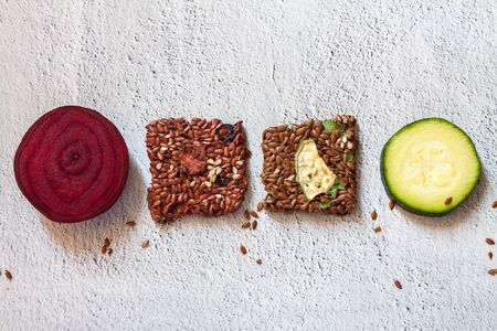 Close up flat lay top view crunchy flax seed crispbread with dry and raw vegetables in the middle white background copy spaceの写真素材