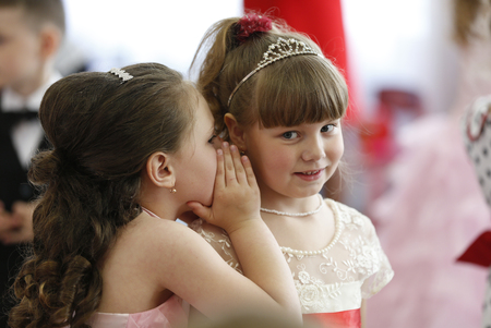 Belarus, the city of Gomel, May 26, 2016. Kindergarten Volotovskaya.On the holiday, a girl whispers in the ear of another girl to a child, girlfriends, a secret.Preschoolers girlfriends.Tell a secretのeditorial素材