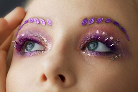 Female eyes with purple make-up. Beautiful extended eyelashes and eyebrows.の写真素材