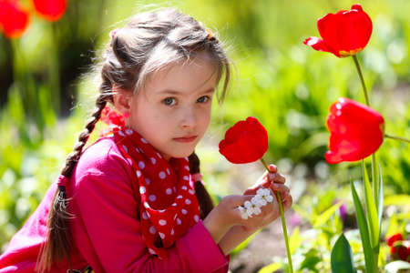 City Gomel, Belarus, May 4, 2017 Fifth kindergarten, graduation day.Unknown girl sitting near red tulips.Smell the flowersのeditorial素材