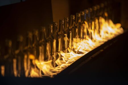 Glassworks. Glass industry. Glass bottle on conveyor on fireの写真素材