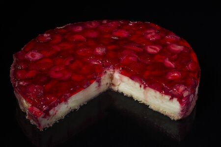 cut piece of cake cheesecake with strawberries in jelly on black backgroundの写真素材