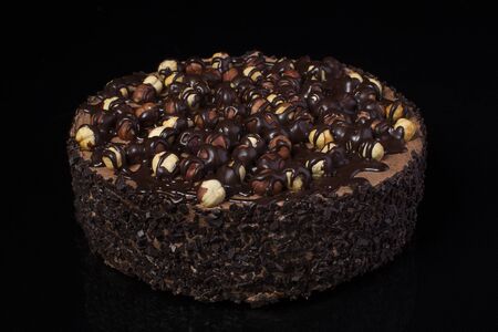 Chocolate cake with hazelnuts with white cream on a black background closeupの写真素材