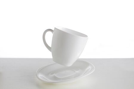 White cup with saucer in a jump on a white background. Jumping cup. Flying dishes on a white background.White dishes on a white backgroundの写真素材