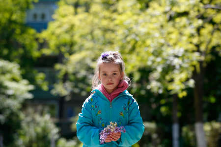 City Gomel, Belarus,April 13, 2017,Kindergarten, senior group, graduation day.Beautiful girl in a spring garden with a lilac in handsのeditorial素材