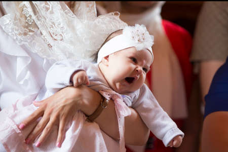 Belarus, the city of Gomel. June 10, 2017. Church at the regional hospital. The baptism of a child.A baby child yawns in his arms at the rite of baptismのeditorial素材