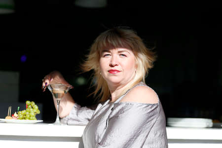 Belarus, Gomel, June 15, 2017.Restaurant Chabarok. Holiday of beauty and fashion, presentation of various cosmetics.Unknown elderly woman with a glass of champagne.Woman alcoholicのeditorial素材