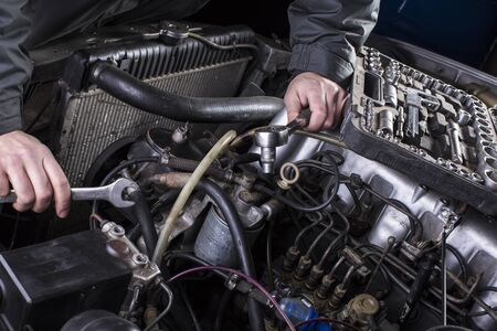 Car engine repair. Diesel engine services. Hands with a mechanic with a wrench repair parts.