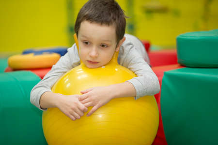 Belarus, Gomel, November 9, 2017. Gomel Children's Center. Children's holiday.Sad child in the gym.Boy on a rubber gymnastic ballのeditorial素材