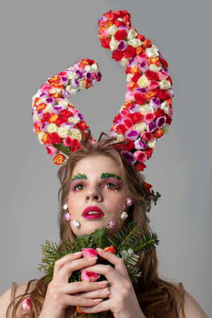 Fairy-tale girl model with floral horns. Maleficent. Spring or summer beauty. Woman in the image of a flower. Flower makeup.の写真素材