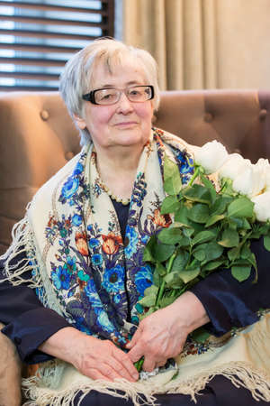Belarus, the city of Gomil, February 08, 2020. Public dining room. Elderly woman with a bouquet of roses.のeditorial素材