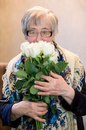 Belarus, the city of Gomil, February 08, 2020. Public dining room. Elderly woman with a bouquet of roses.のeditorial素材