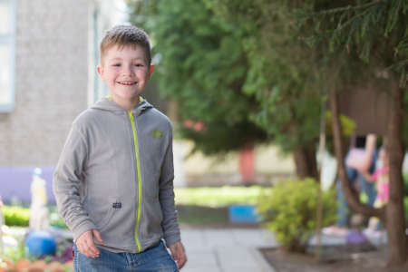 Belarus, the city of Goml, April 26, 2019. Photosession in kindergarten.Joyful boy walks down the street. Merry child smiles against the background of the city. Preschool child.のeditorial素材