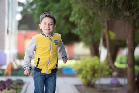 Belarus, the city of Goml, April 26, 2019. Photosession in kindergarten.A smiling preschooler walks along the street. A merry child in the background of the city.のeditorial素材