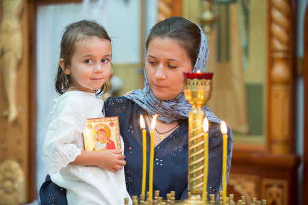 Belarus, the city of Gomil, July 31, 2019. City church. Orthodox baptism. Mother and child in a church by candlelight. Woman with a baby in the temple.のeditorial素材