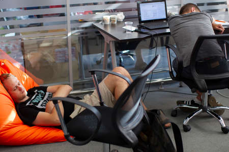 Belarus, Minsk city, August 06, 2017. Programmers Office. Tired IT people sleep at work. Two men...