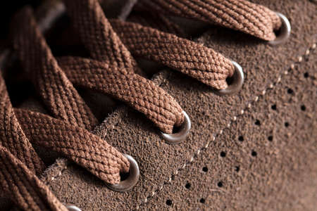 Part of a suede boot with laces. A fragment of brown shoes. A piece of sneaker.の写真素材