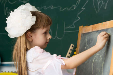 A preschool girl is reading a book. The child is in the library. Read books.