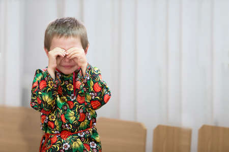 The little boy is crying.Kid covered his face with his hands