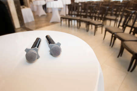 Table with microphones on the background of the room with rows of chairs. Press conferenceの写真素材