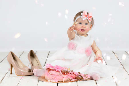 Beautiful baby bathes in a basin and eats a red apple. Little girl in one year old.の写真素材